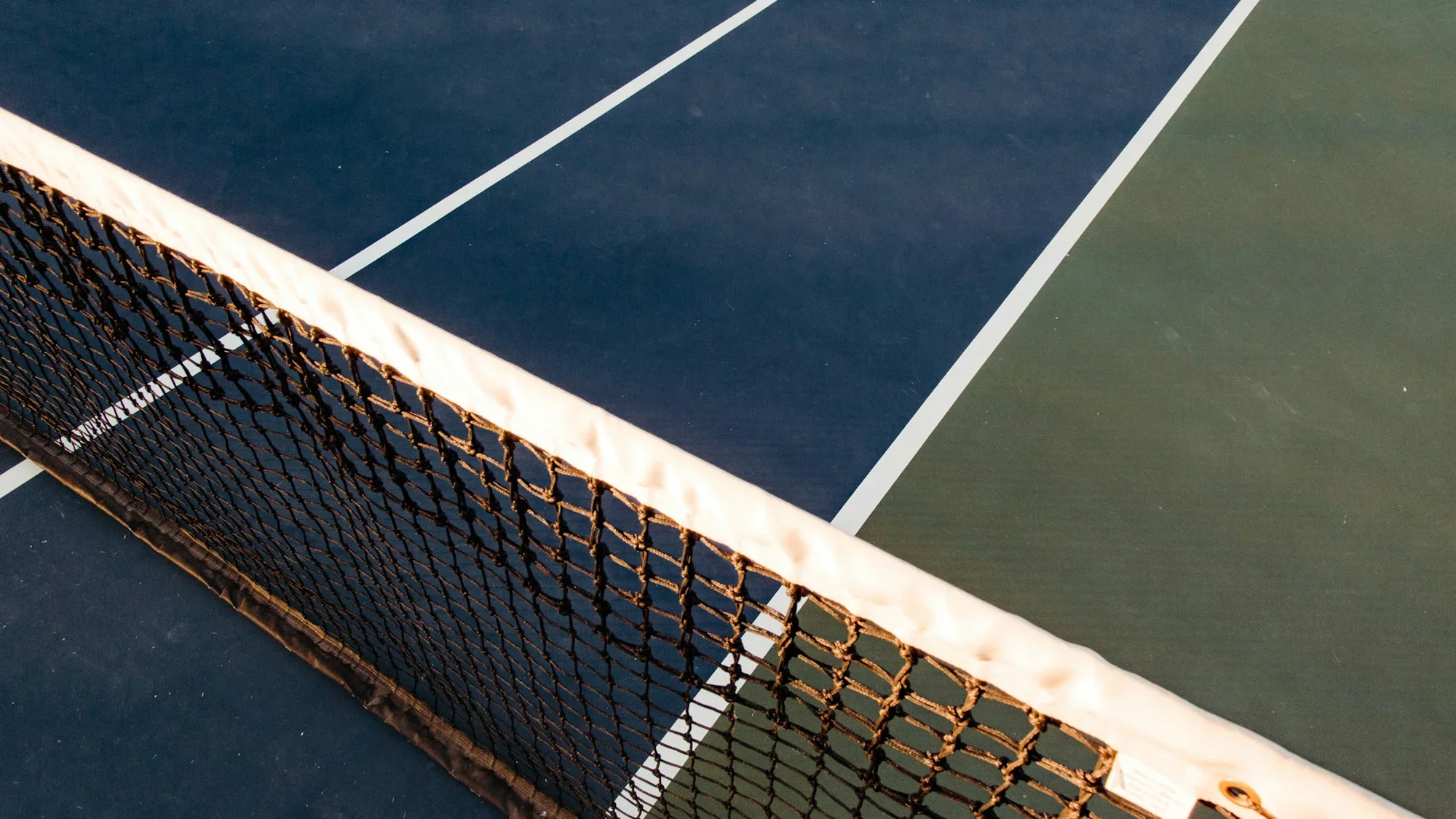 Low evening sunlight falling across a tennis court and net